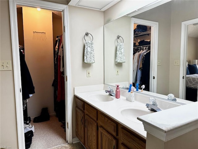full bath featuring double vanity, a walk in closet, and a sink