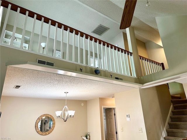 stairs featuring a textured ceiling, high vaulted ceiling, visible vents, and a notable chandelier