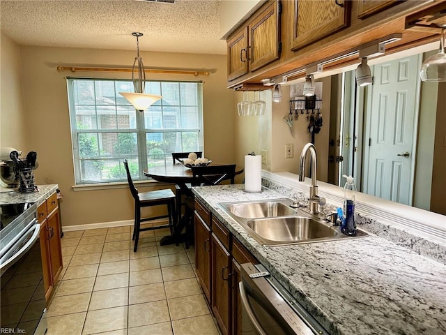 kitchen featuring pendant lighting, brown cabinets, a sink, light tile patterned floors, and stainless steel appliances