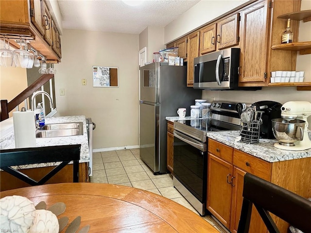 kitchen featuring open shelves, brown cabinets, a sink, light tile patterned floors, and stainless steel appliances