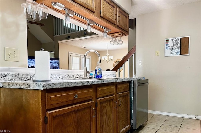kitchen with stainless steel dishwasher, a sink, light tile patterned floors, baseboards, and a notable chandelier
