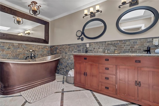 bathroom featuring a freestanding bath, an inviting chandelier, double vanity, a wainscoted wall, and ornamental molding