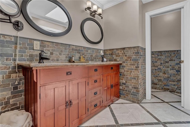 full bath with crown molding, tile walls, a wainscoted wall, and double vanity