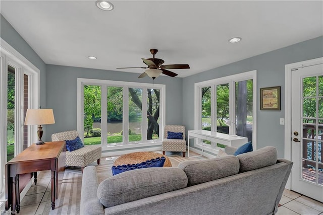 living area with light tile patterned flooring, a ceiling fan, recessed lighting, and a water view