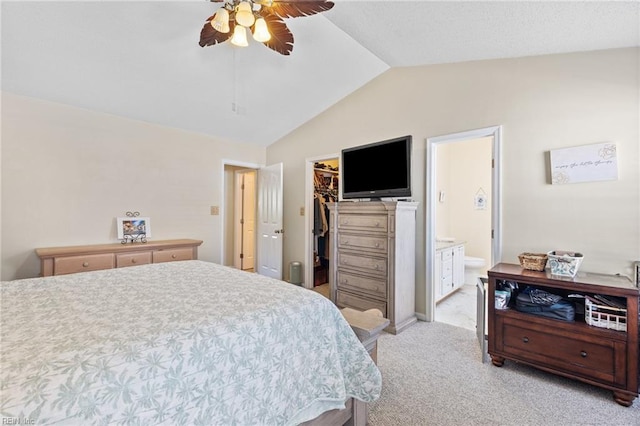 bedroom with a closet, a spacious closet, ensuite bathroom, light carpet, and lofted ceiling