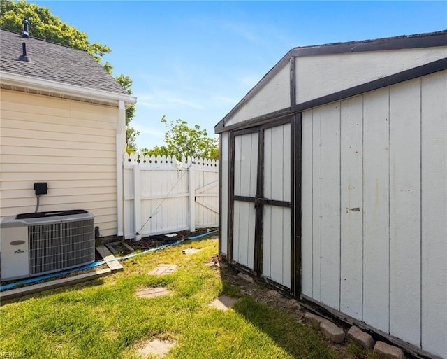 view of shed with central AC unit and fence