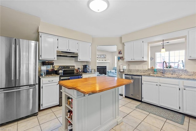 kitchen featuring white cabinets, light tile patterned flooring, a sink, stainless steel appliances, and under cabinet range hood