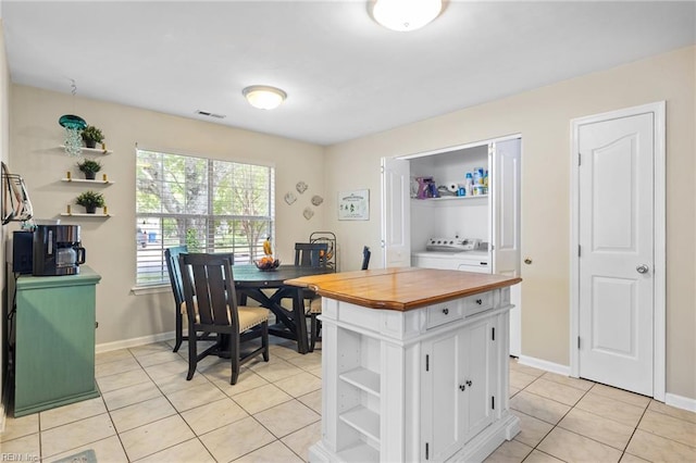kitchen with washer / clothes dryer, open shelves, wood counters, and visible vents
