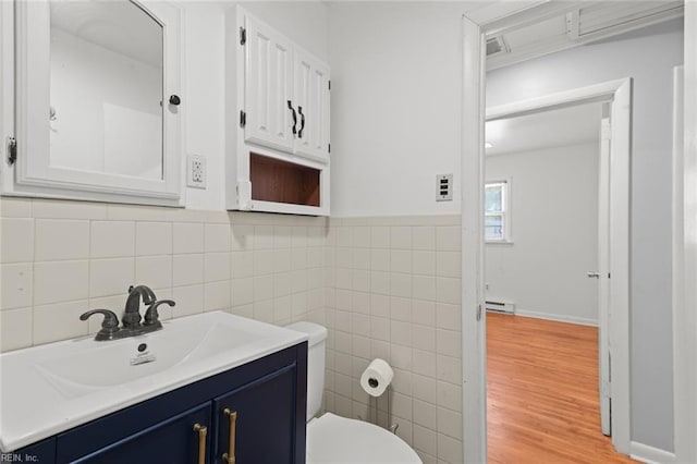 bathroom featuring tile walls, wood finished floors, vanity, a baseboard radiator, and toilet