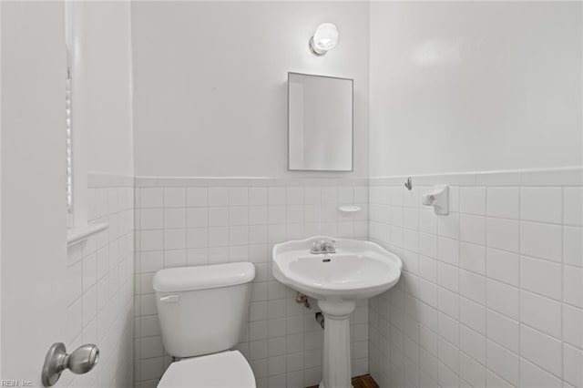 bathroom featuring tile walls, wainscoting, and toilet