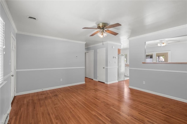 empty room featuring visible vents, ornamental molding, ceiling fan, and wood finished floors
