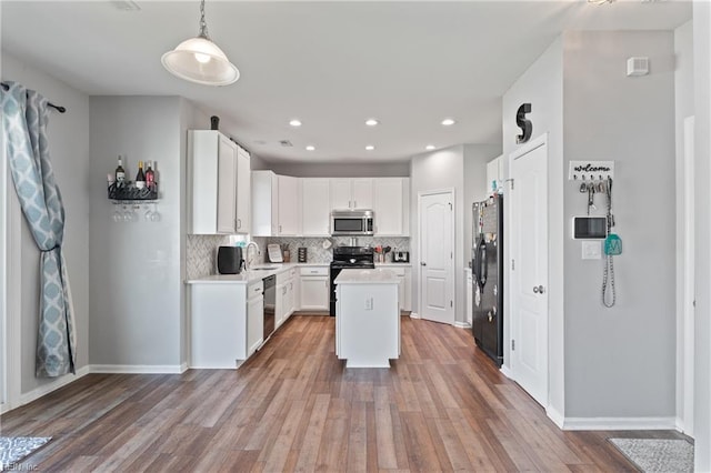 kitchen with decorative backsplash, wood finished floors, light countertops, a sink, and black appliances