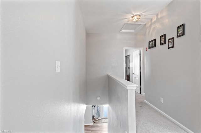 corridor with baseboards, an upstairs landing, and attic access
