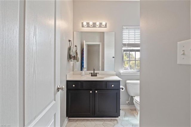 bathroom with baseboards, tile patterned floors, toilet, and vanity