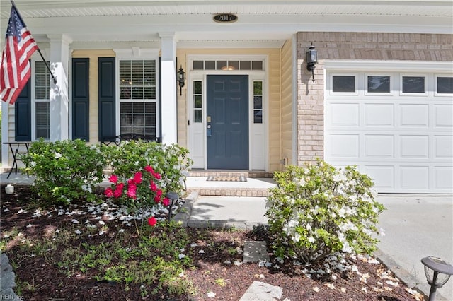 property entrance with a porch, brick siding, and an attached garage