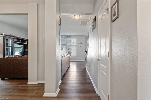 corridor featuring baseboards, dark wood finished floors, and visible vents