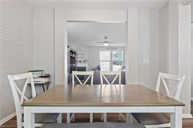 dining space featuring baseboards, a ceiling fan, and wood finished floors