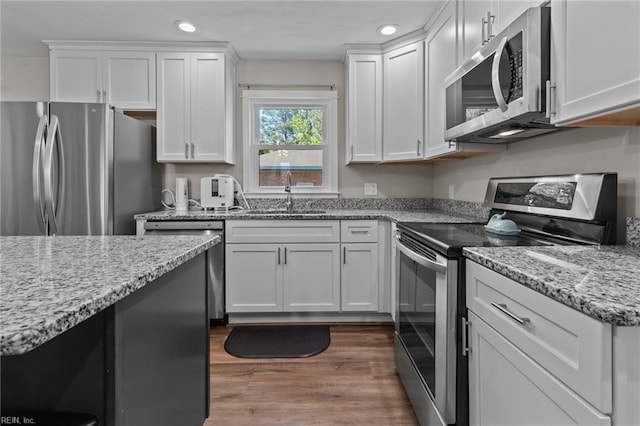 kitchen with recessed lighting, a sink, white cabinets, and stainless steel appliances