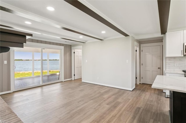 unfurnished living room with light wood-type flooring, recessed lighting, baseboards, and beam ceiling