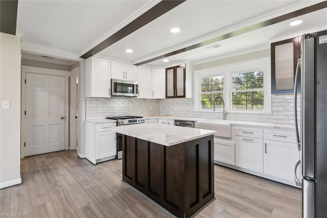 kitchen with crown molding, tasteful backsplash, a sink, white cabinets, and stainless steel appliances