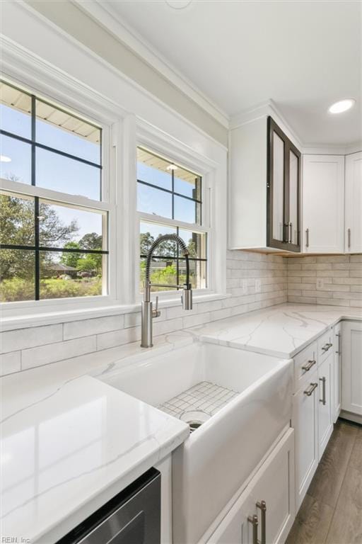kitchen with crown molding, backsplash, white cabinets, and wood finished floors