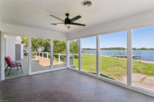 unfurnished sunroom featuring a water view, ceiling fan, visible vents, and a wealth of natural light