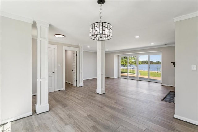 unfurnished dining area with crown molding, baseboards, decorative columns, and wood finished floors