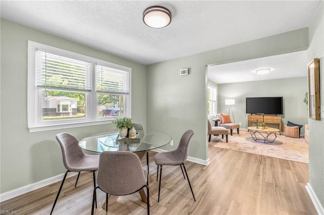 dining area with a textured ceiling, baseboards, and wood finished floors