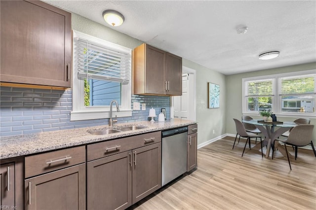 kitchen featuring a sink, light wood-style floors, a textured ceiling, baseboards, and stainless steel dishwasher