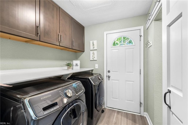 clothes washing area featuring light wood-style floors, baseboards, cabinet space, and washer and clothes dryer