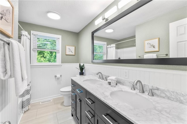 bathroom featuring a sink, a wainscoted wall, toilet, and a shower with curtain