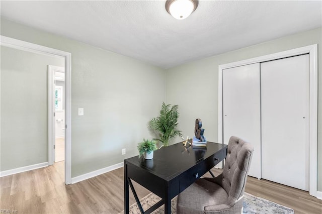 office with baseboards and light wood-style flooring