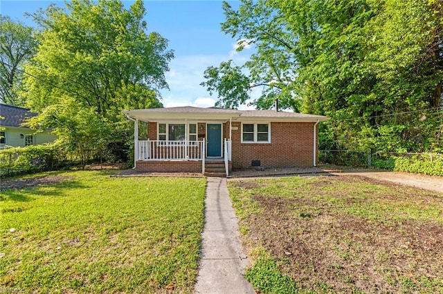 view of front of property with fence, covered porch, brick siding, and a front yard