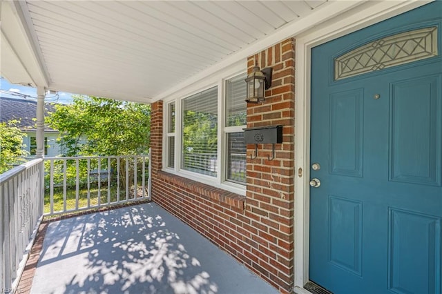property entrance with a porch and brick siding