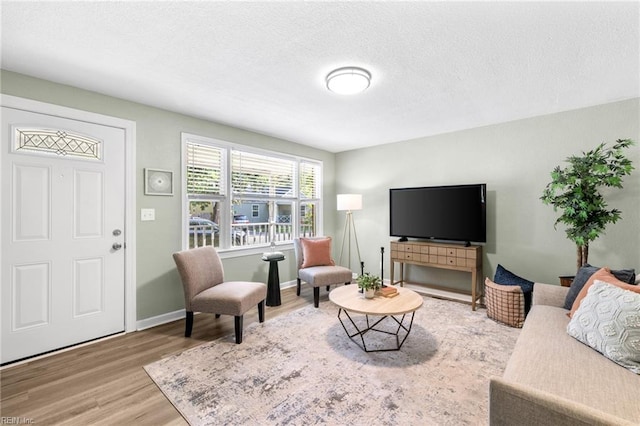 living room with baseboards, a textured ceiling, and wood finished floors