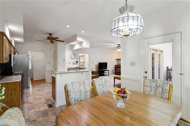 dining space with recessed lighting, stone finish flooring, and ceiling fan with notable chandelier