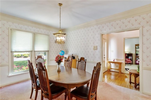 dining room with ornamental molding, light wood finished floors, a notable chandelier, and wallpapered walls