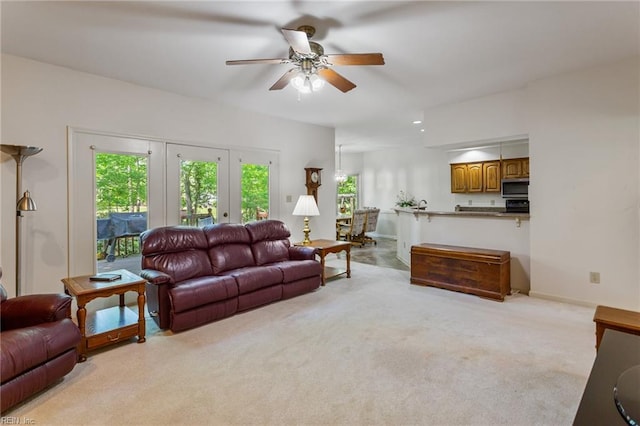 living room with baseboards, plenty of natural light, ceiling fan, and light colored carpet