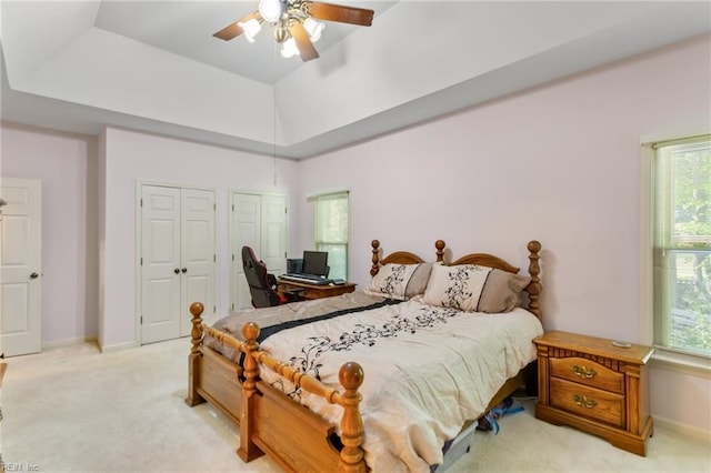 bedroom with a ceiling fan, baseboards, light carpet, and two closets