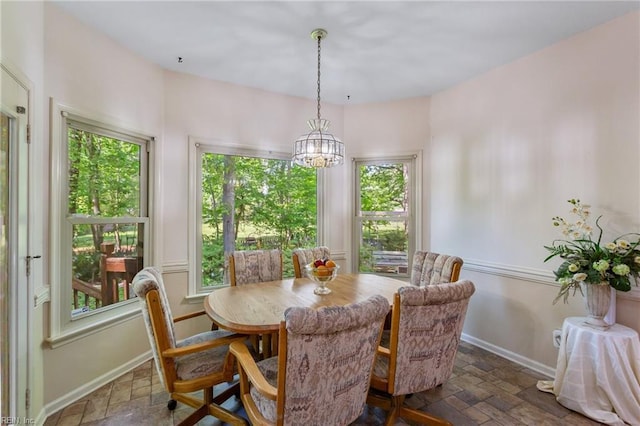 dining area featuring a wealth of natural light, a chandelier, and stone tile floors
