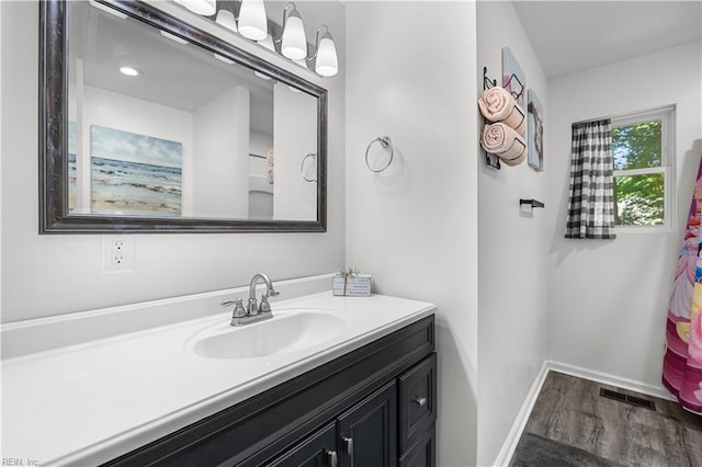 bathroom with vanity, baseboards, wood finished floors, and visible vents