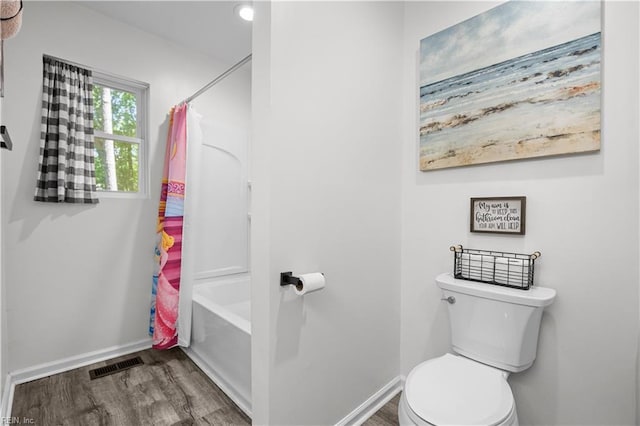bathroom with visible vents, wood finished floors, shower / tub combo, baseboards, and toilet