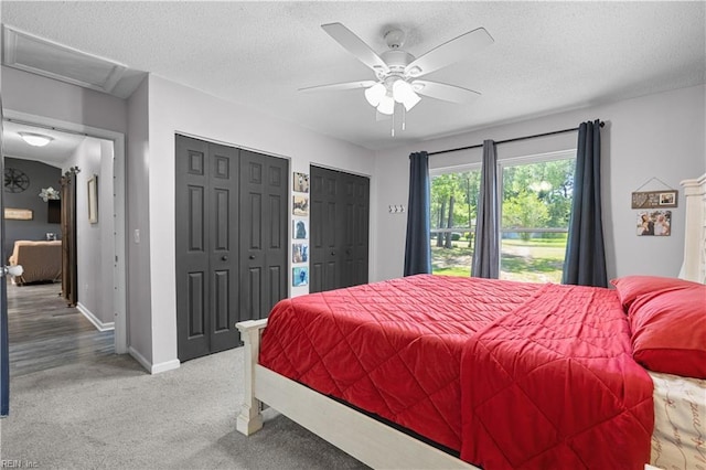 bedroom featuring attic access, a textured ceiling, baseboards, two closets, and light carpet