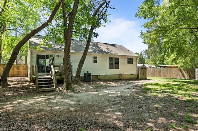 rear view of property featuring a fenced backyard, a storage unit, an outbuilding, and a deck