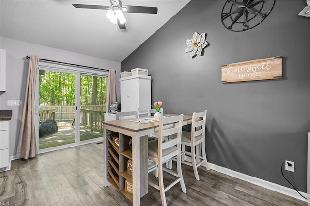 dining area with a ceiling fan, baseboards, wood finished floors, and lofted ceiling