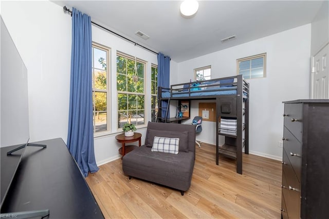bedroom featuring visible vents, light wood-style floors, and baseboards