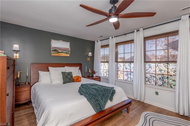 bedroom with baseboards, multiple windows, wood finished floors, and visible vents