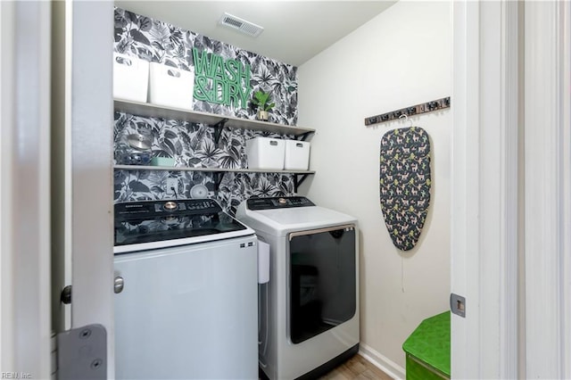 laundry area with laundry area, visible vents, baseboards, light wood-style floors, and separate washer and dryer