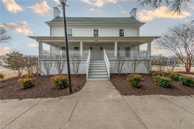 view of front of property with covered porch, a chimney, and stairs