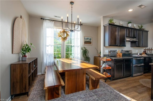 dining area featuring wood finished floors, recessed lighting, a chandelier, and visible vents